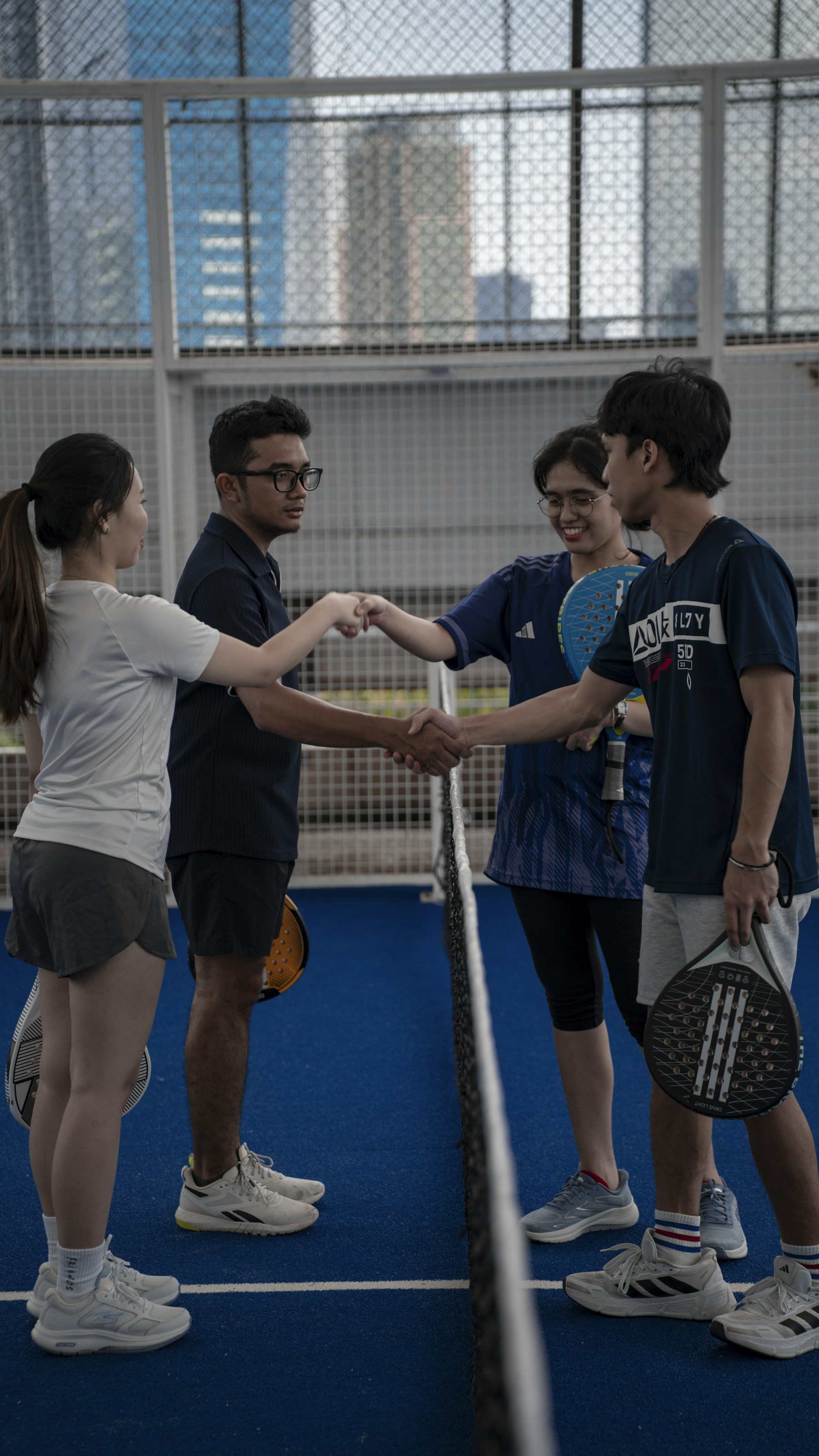 Four padel players greeting one another at the net