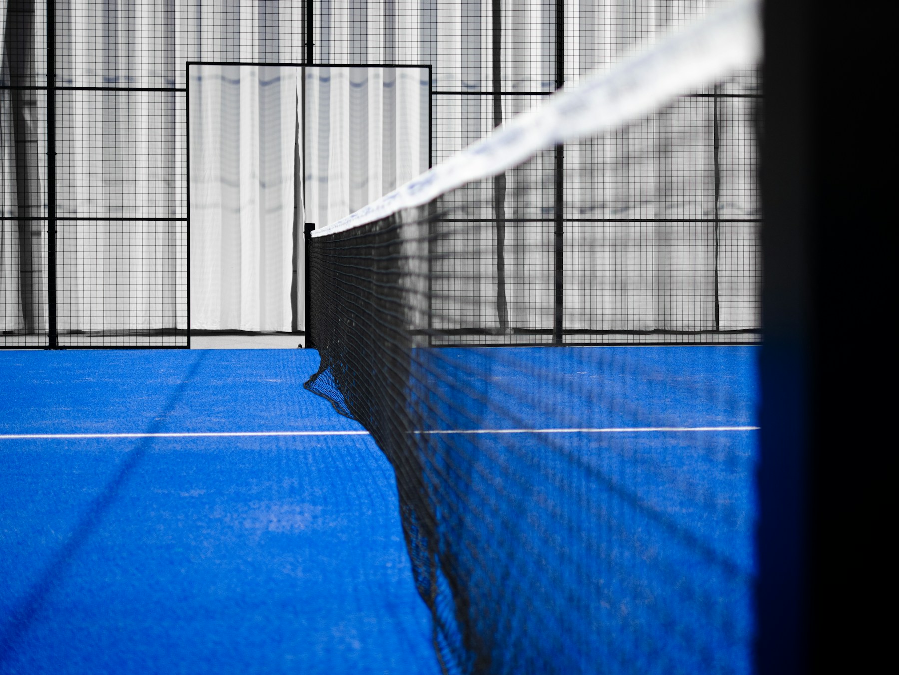 The net and glass enclosure of a contemporary indoor padel court